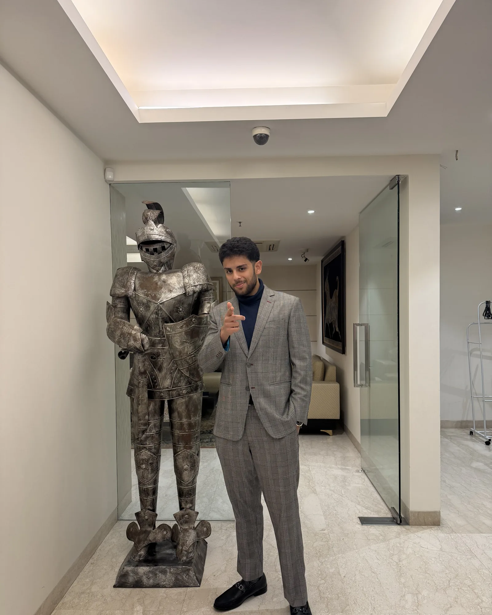 Rocky V. Bawa in a suit beside a suit of armor